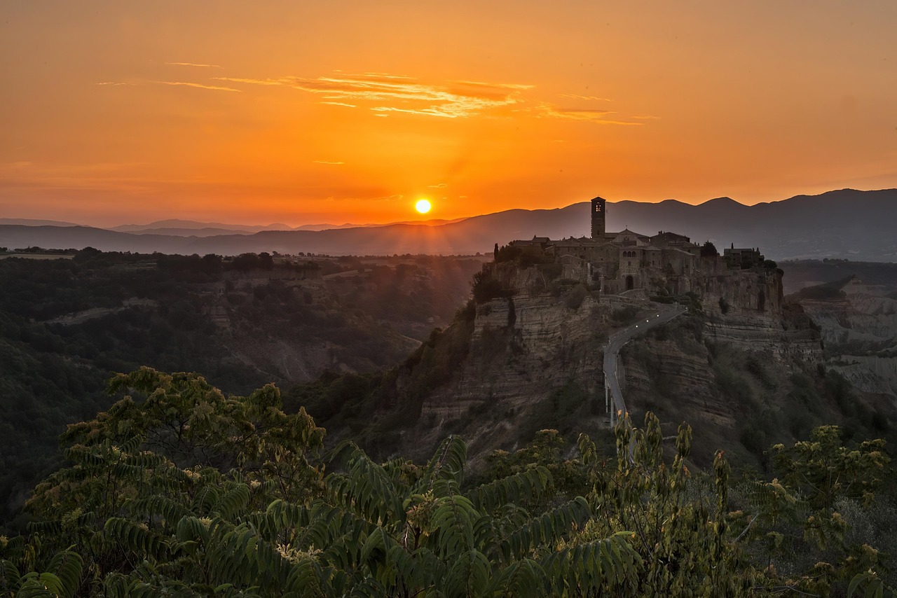 Sunset view overlooking Civita di Bagnoregio, Italy, with warm light illuminating the hilltop village and surrounding valley.